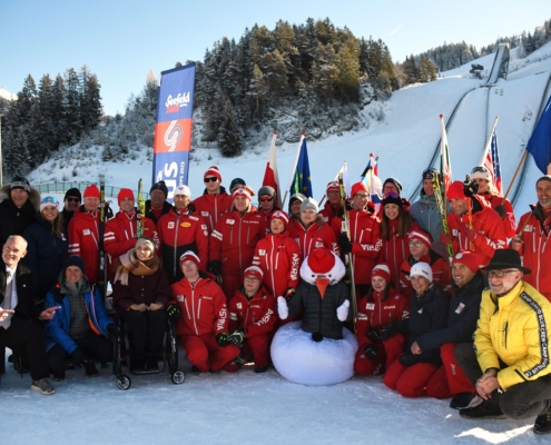 Gruppenfoto mit den Sportlern, Trainern und dem Maskottchen (Snowi)